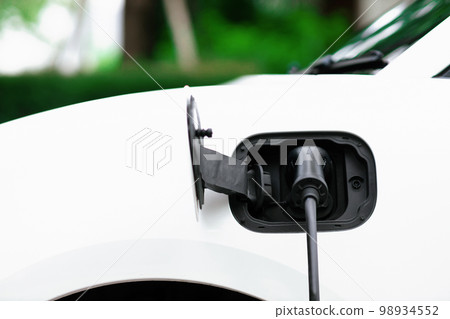 EV car plugged-in with cable from progressive home charging station. EV car plugged-in with cable from progressive home charging station. 98934552