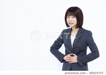 A business woman in her thirties who has a stomach ache A business woman in her thirties who has a stomach ache 98934747
