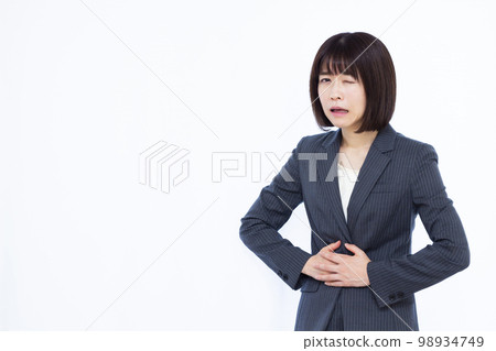 A business woman in her thirties who has a stomach ache A business woman in her thirties who has a stomach ache 98934749