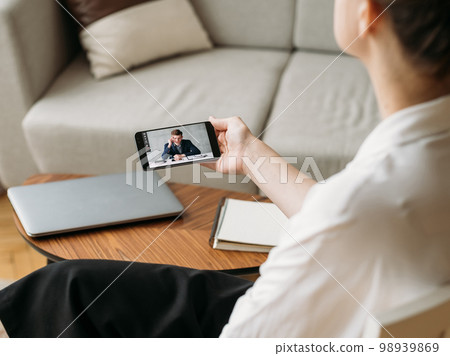 Mobile conference. Video call. Remote interview. Business partners discussing work online on phone screen at home office workplace. Mobile conference. Video call. Remote interview. Business partners discussing work online on phone screen at home office workplace. 98939869