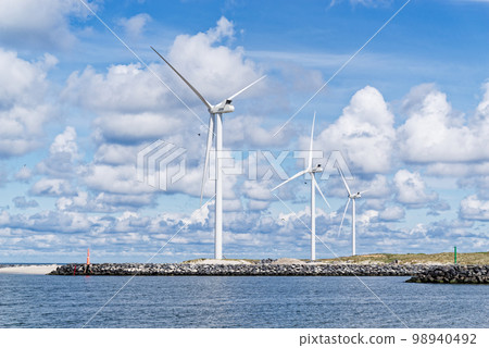Wind turbines on the shore against cloudy sky Wind turbines on the shore against cloudy sky 98940492