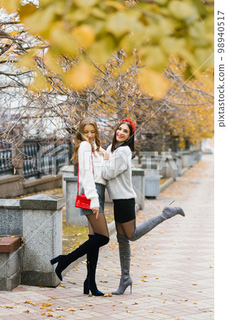 Photos of two girls, charming friends walking in the autumn park, enjoying the weather Photos of two girls, charming friends walking in the autumn park, enjoying the weather 98940517