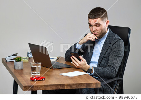 businessman sitting on chair at desk and talking on the phone businessman sitting on chair at desk and talking on the phone 98940675