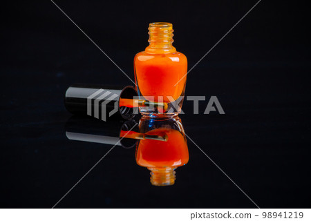 Close up of orange nail polish bottle on black background. Concept of manicure or pedicure. 98941219