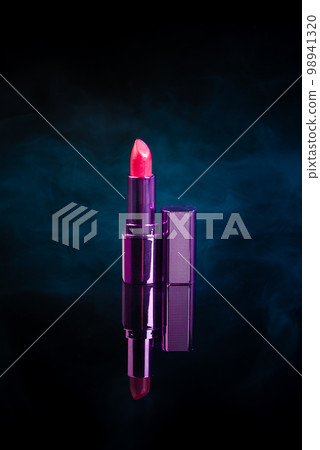 Vertical shot of red lipstic on reflective surface. Steam vapor on black background. 98941320