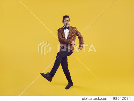 Funny and happy young black man in a party outfit dancing isolated on a yellow background Funny and happy young black man in a party outfit dancing isolated on a yellow background 98942054