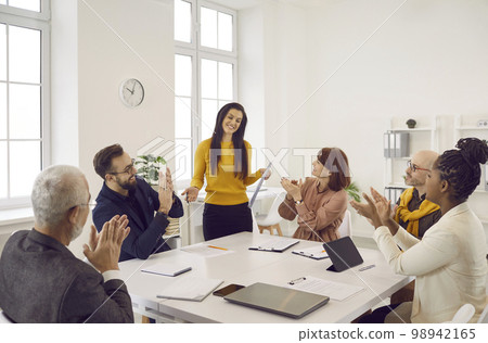 Woman receives ovation for successful presentation at work meeting with team of colleagues 98942165
