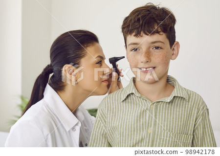 Otolaryngologist examining a little child and using an otoscope to check his ears 98942178