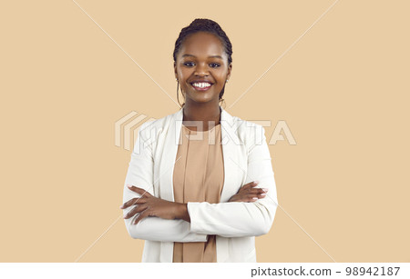Portrait of young smiling african woman standing with folded arms and looking at camera. 98942187