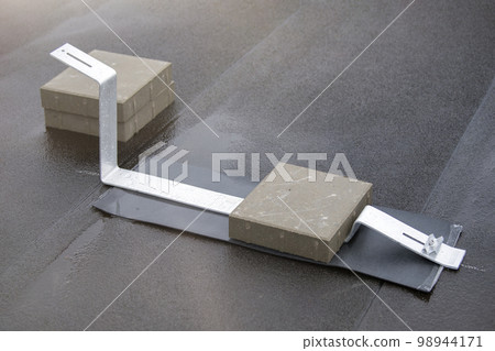 Brackets for installing solar panels on the roof of a building. Aluminum fixtures for solar modules are placed on the roof before the panels are installed. Brackets for installing solar panels on the roof of a building. Aluminum fixtures for solar modules are placed on the roof before the panels are installed. 98944171