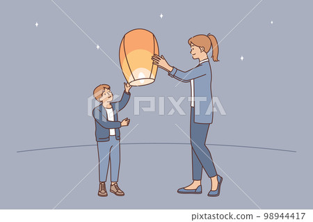 Teenage boy together with older sister launch air fire lantern standing on street under starry sky Teenage boy together with older sister launch air fire lantern standing on street under starry sky 98944417