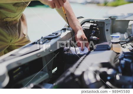 Auto mechanic checking engine oil 98945580