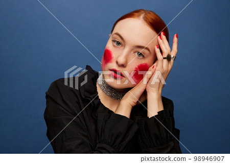 Beetroot cheeks. Young beautiful girl eating beet over blue studio background. Food pop art photography. Complementary colors 98946907