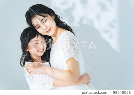 一個女人和一個女孩依偎在一起 父母和孩子的美麗形象 98948038