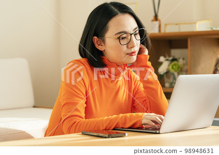 A woman watching a computer at home A woman watching a computer at home 98948631