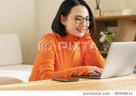 A woman watching a computer at home 98948632