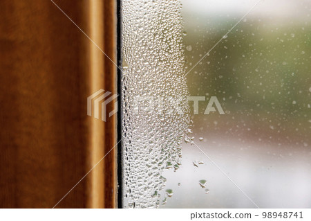 Misted wet window glass with water drops close up Misted wet window glass with water drops close up 98948741