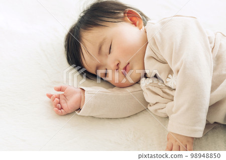 A 0-year-old baby taking a nap on a rug 98948850