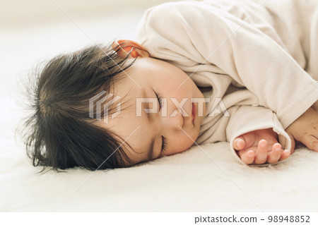 A 0-year-old baby taking a nap on a rug 98948852