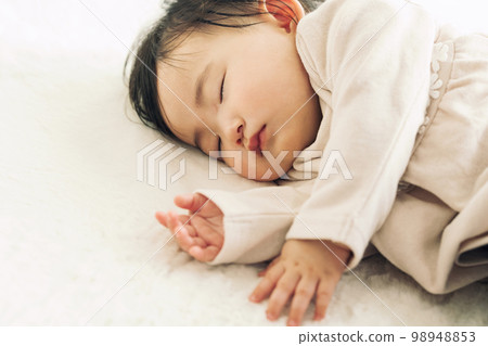A 0-year-old baby taking a nap on a rug 98948853