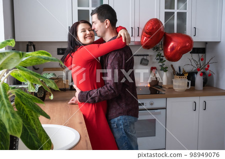 Man and woman in love date at home in kitchen happy hugs. Valentine's Day, happy couple, love story. Love nest, housing for young family Man and woman in love date at home in kitchen happy hugs. Valentine's Day, happy couple, love story. Love nest, housing for young family 98949076