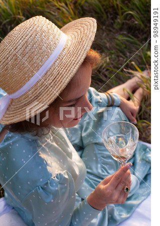 A woman in blue dress sits on a picnic in a park with panoramic view A woman in blue dress sits on a picnic in a park with panoramic view 98949191