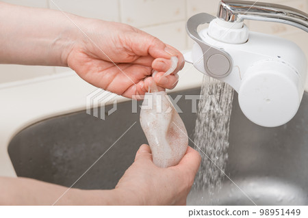 [A middle-aged housewife prepares a squid and washes the inside of its body] 98951449