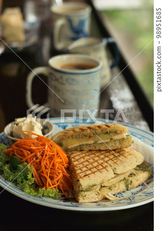 Vertical shot of a plate of vegan panini with carrot salad and coffee for breakfast 98951685
