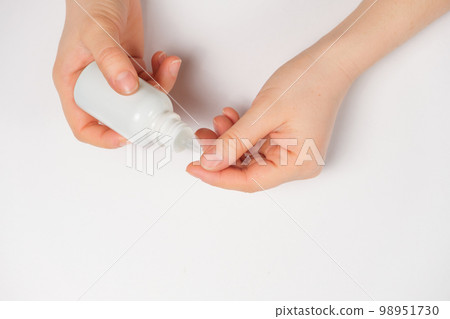 Woman applies cuticle remover to nails on white background top view 98951730