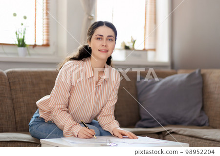Purchase of real estate. Portrait of smiling woman fills documents. Concept of leasing, loan and mortgage Purchase of real estate. Portrait of smiling woman fills documents. Concept of leasing, loan and mortgage 98952204