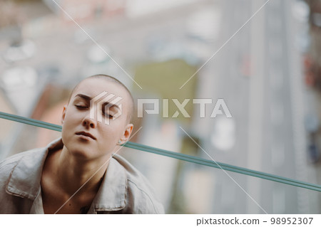 High angle view of young unhappy woman with cancer sitting in a window. 98952307