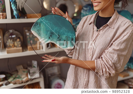 Woman decorator demonstrate handmade epoxy resin glass tray with sea waves standing in own studio 98952328