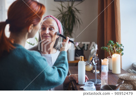 Caregiver helping her client with a make up. 98952479