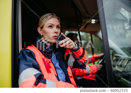Portrait of young woman doctor sitting and talking in to walkie-talkie in ambulance car. Portrait of young woman doctor sitting and talking in to walkie-talkie in ambulance car. 98952535