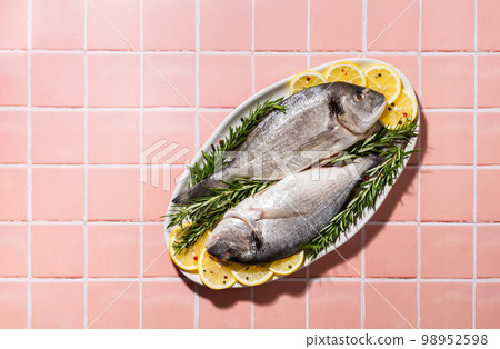 Raw Dorada fish in hard light Raw Dorada fish in hard light 98952598
