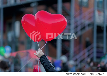 Two LED balloons in the form of scarlet burning hearts in evening in girl's hand. Romantic background, Valentine's Day Two LED balloons in the form of scarlet burning hearts in evening in girl's hand. Romantic background, Valentine's Day 98952674