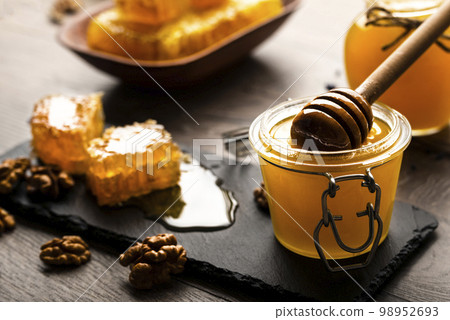 Honeycomb on slate tray with honey and nuts on kitchen table 98952693