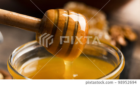 Honey on wooden honey-dipper closeup food background 98952694