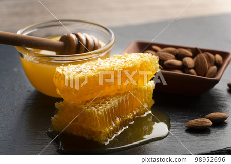 Slate tray with honey almonds and honeycomb on kitchen table 98952696