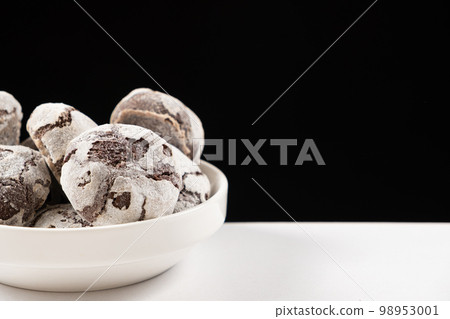 Chocolate chip cookies with cocoa and powdered sugar on a plate on a black background. Chocolate chip cookies with cocoa and powdered sugar on a plate on a black background. 98953001