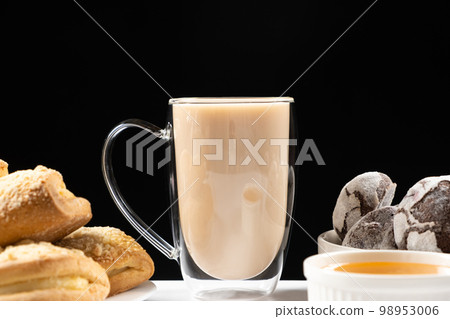 Tea with milk in a glass cup with a double bottom and cookies with gingerbread on a black background 98953006