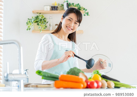 Smiley middle woman cooking in the kitchen Smiley middle woman cooking in the kitchen 98953080