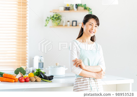 A smiling middle woman standing in the kitchen 98953528