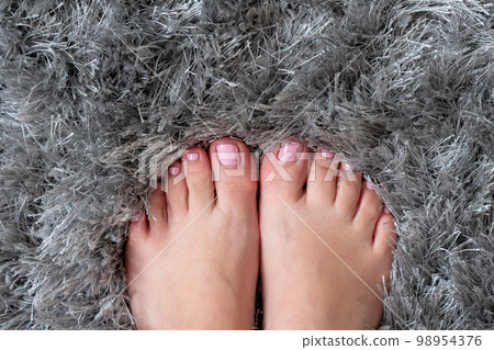Closeup of female feet and toes on grey carpet background. Healthy feet concept 98954376