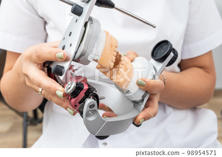 Dentist holding dental articulator with dental gypsum prosthesis model in dental laboratory Dentist holding dental articulator with dental gypsum prosthesis model in dental laboratory 98954571