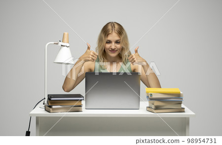 Cheerful office worker business student woman freelancer showing two thumbs up in front of laptop while speaking with a partners or clients. Cheerful office worker business student woman freelancer showing two thumbs up in front of laptop while speaking with a partners or clients. 98954731