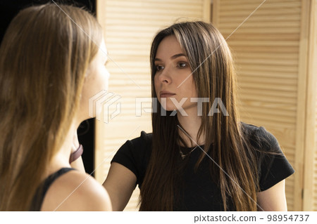 A beautiful young woman with long hair doing makeup for a wedding or photo shoot. Work of a make-up artist. The morning of the bride. Decorative cosmetics. A beautiful young woman with long hair doing makeup for a wedding or photo shoot. Work of a make-up artist. The morning of the bride. Decorative cosmetics. 98954737