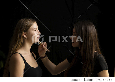 Make-up artist working with brush on model face. Portrait of young blonde woman in beauty salon interior. Process of making makeup. Applying toner to skin. Make-up artist working with brush on model face. Portrait of young blonde woman in beauty salon interior. Process of making makeup. Applying toner to skin. 98954738