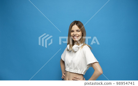 Portaite of happy young beautiful woman with a big white headphones on a neck. Portaite of happy young beautiful woman with a big white headphones on a neck. 98954741