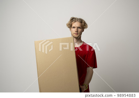 Young delivery man, courier in red cap and t-shirt standing with big parcel post box isolated over white background. Young delivery man, courier in red cap and t-shirt standing with big parcel post box isolated over white background. 98954883